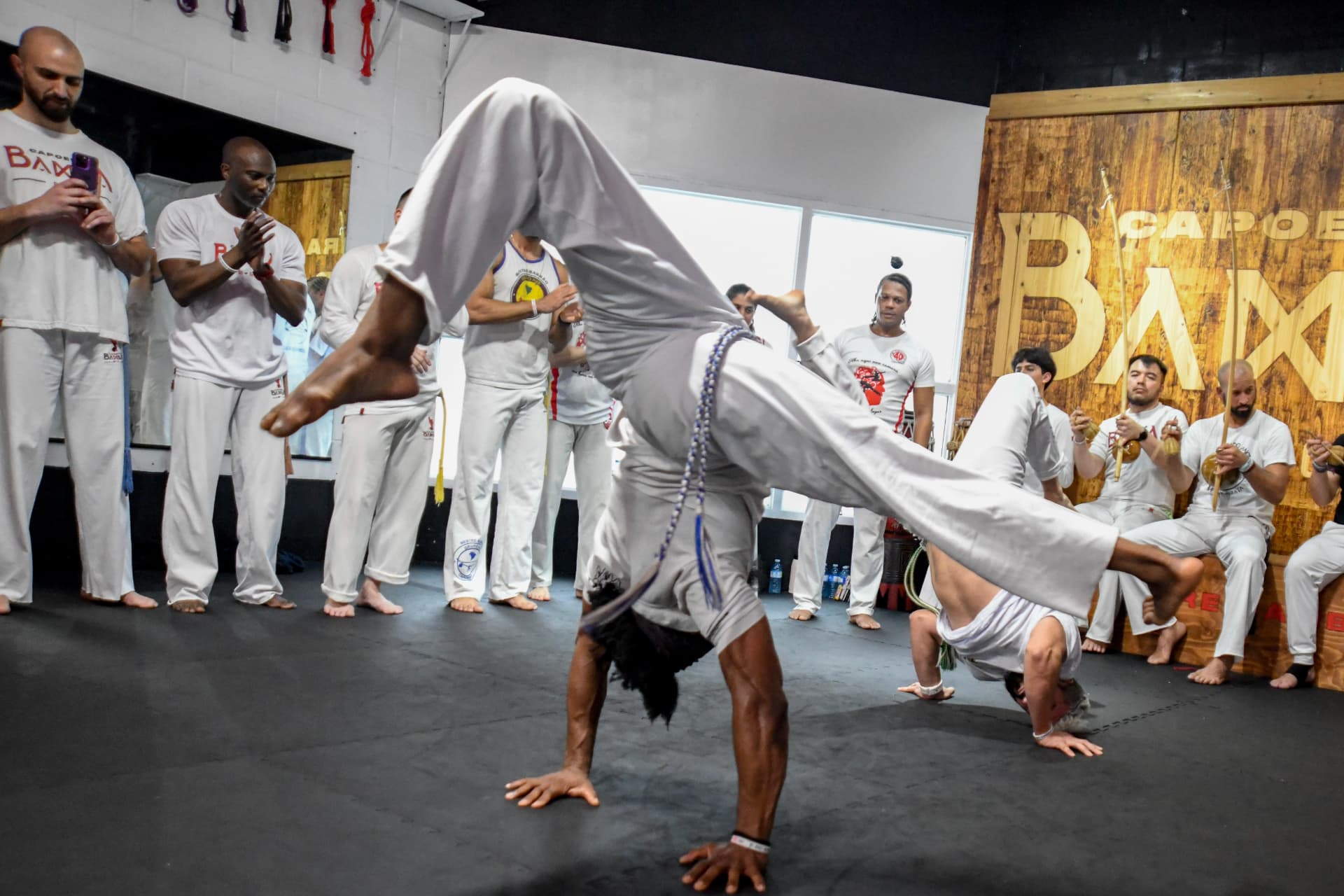 Capoeira roda with a student mid-handstand kick